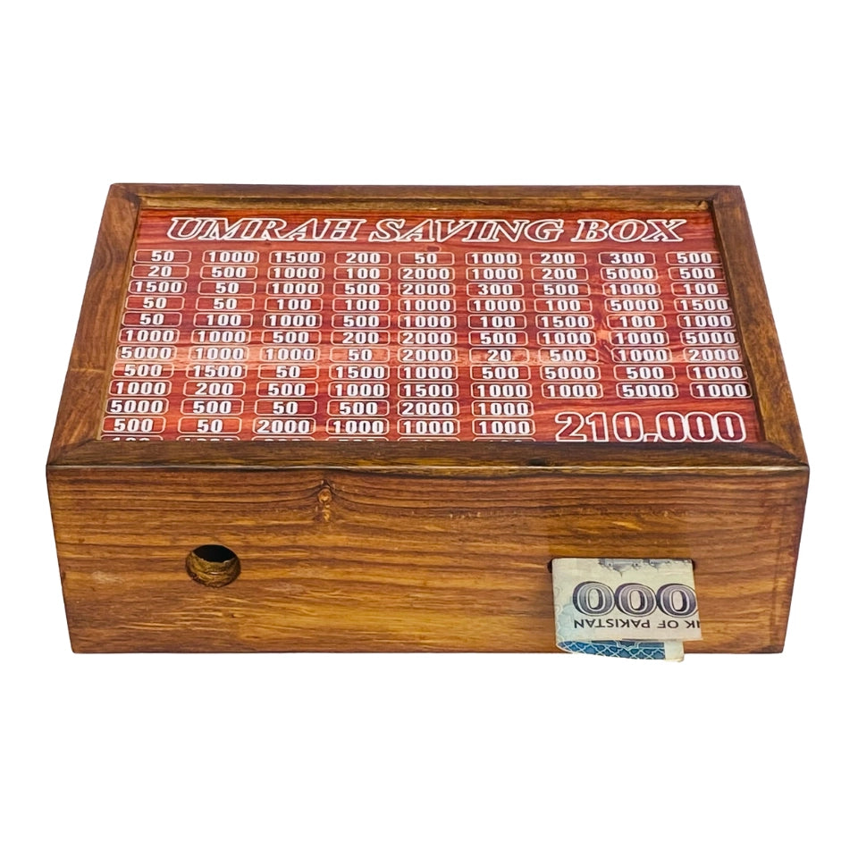 Wooden Umrah Saving Box with numbered compartments for Pakistani Rupee amounts on red background. Traditional Islamic savings method for pilgrimage fund with 210,000 PKR goal.