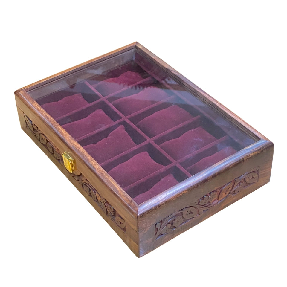 Handcrafted wooden watch box with glass lid open, showing burgundy velvet-lined compartments arranged in a grid pattern, featuring ornate carved details on the wooden frame