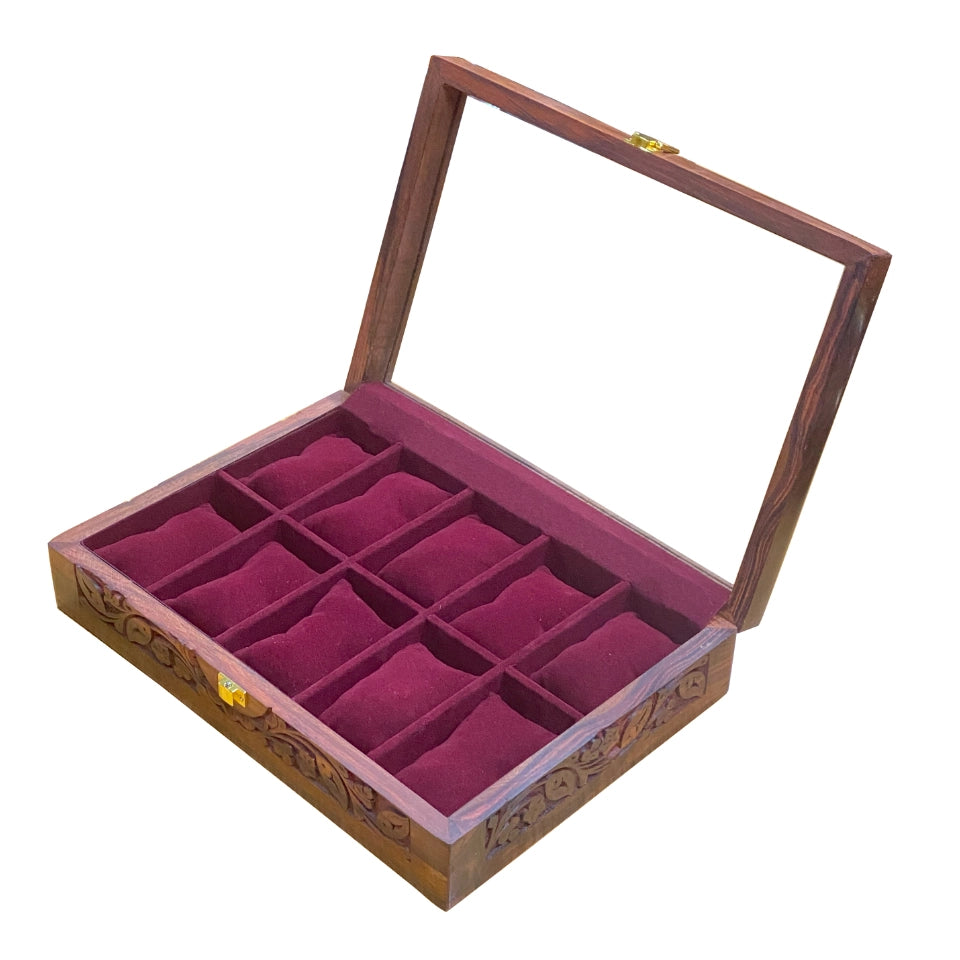 Handcrafted wooden watch box with glass lid open, showing burgundy velvet-lined compartments arranged in a grid pattern, featuring ornate carved details on the wooden frame